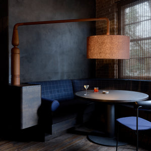 Juniper berry-blue furniture sits against blackened walls inside this cosy bar, laboratory and store that design studio YSG has created in Sydney for gin brand Four Pillars.