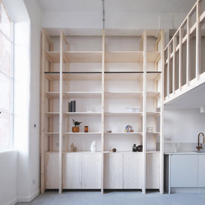 Structural ash and pine joinery – including a staircase, mezzanine and double-height storage wall – delineate the space within this refurbished, open-plan apartment in London by EBBA Architects.